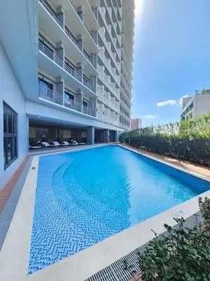 a swimming pool in front of a building at Happy Haven at Lush Makati in Manila