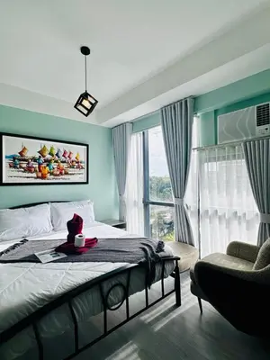 a bedroom with a bed and a chair and a window at Enter Home McKinley with a View in Manila