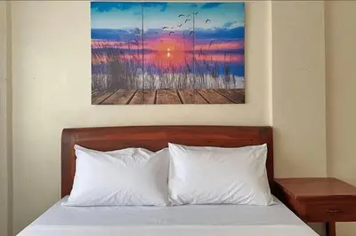 a bed with white pillows and a painting on the wall at Lawton Residences Studio Room 3G in Manila