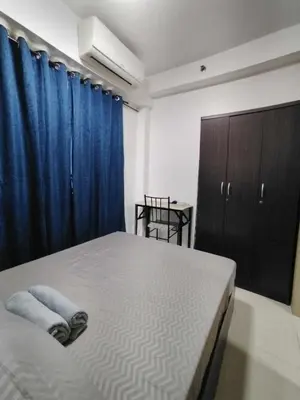 a bedroom with a bed and a blue curtain at Shore Residences - 1 Bedroom Condo Unit in Manila