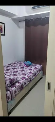a small bed in a room with a purple comforter at Derick Staycation With Balcony Moa View in Manila