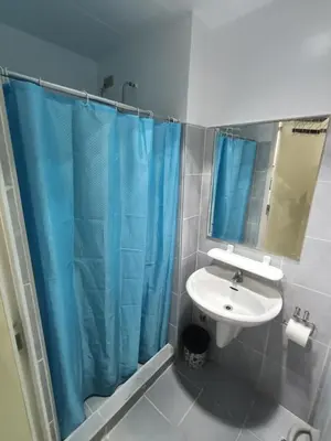 a bathroom with a sink and a blue shower curtain at Derick Staycation With Balcony Moa View in Manila