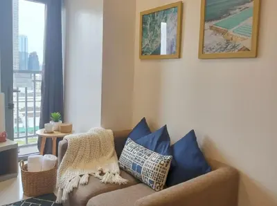 a living room with a brown couch with blue pillows at Heart of Ortigas Center in Manila