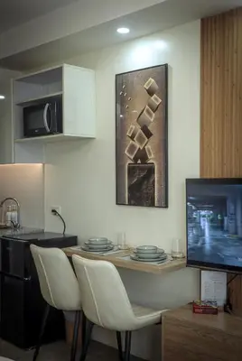 a kitchen with a table with chairs and a television at A Scandinavian-inspired studio in Silang in Bayabasan
