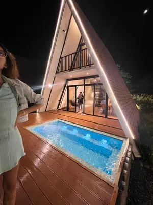 a woman standing next to a swimming pool on a deck at Villa Teodora in Biñan