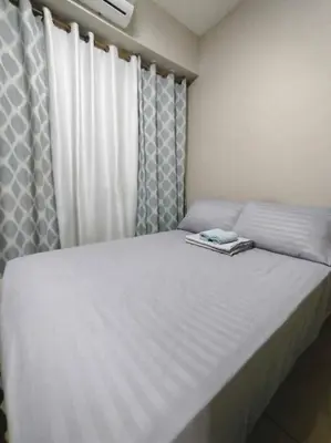 a bedroom with a large white bed with curtains at Near MOA at SHORE RESIDENCES 1BR with balcony -unlimited WIFI in Manila