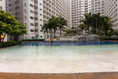 a large swimming pool with palm trees and buildings at Shore Residences Tower D - Two Bedroom with Balcony in Manila
