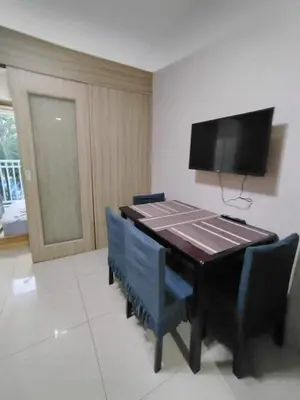 a dining room table with chairs and a flat screen tv at Shore Residences - 1 Bedroom with Balcony in Manila