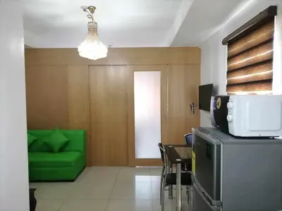 a living room with a green couch and a tv at spacious 1 br fully furnished condo in Manila