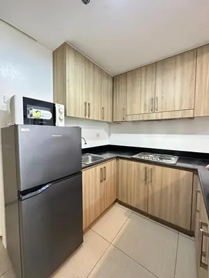 a kitchen with a black refrigerator and wooden cabinets at 2br shore residences staycation in Manila