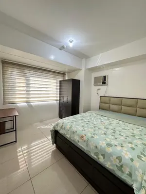 a bedroom with a bed and a desk and a window at 2br shore residences staycation in Manila