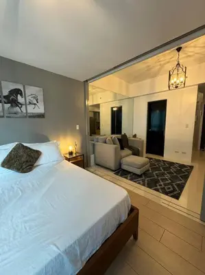 a bedroom with a large bed and a living room at One Uptown Stylish Retro Suite in Manila
