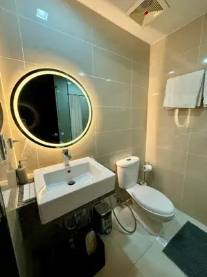 a bathroom with a sink and a toilet and a mirror at One Uptown Stylish Retro Suite in Manila