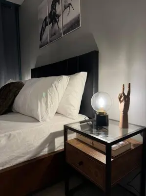 a bedroom with a bed and a table with a lamp at One Uptown Stylish Retro Suite in Manila