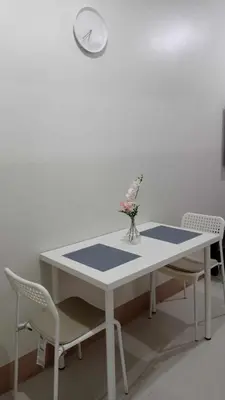a white table with chairs and a clock on a wall at Casa Laelia in Manila