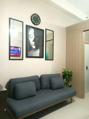 a living room with a blue couch and a clock at 1 Bedroom with Balcony Near MOA in Manila