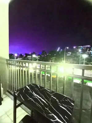 a bench sitting on top of a balcony at night at 1 Bedroom with Balcony Near MOA in Manila