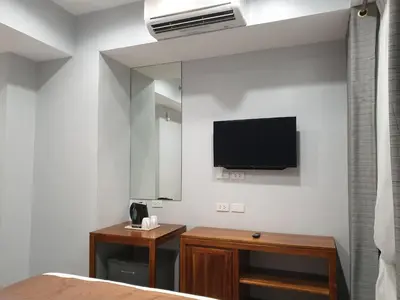 a bedroom with a mirror and a tv on the wall at Leez Inn Makati in Manila