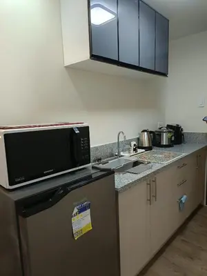 a kitchen with a microwave oven and a sink at Miranda's Suites by Fullerton in Puting Kahoy