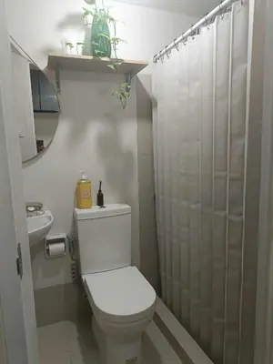 a white bathroom with a toilet and a shower at Miranda's Suites by Fullerton in Puting Kahoy