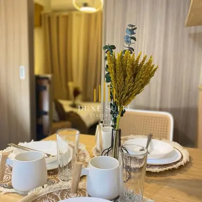a table with plates and cups and a vase with flowers at Aesthetic walking distance to MOA,near NAIA AIRPORT with NETFLIX,MINIVIDEOKE,BOARDGAMES-DUXE2 in Manila