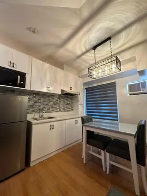 a kitchen with white cabinets and a table with chairs at Newly Reneuvated Fully Furnished Condo Apartment in the Heart of Mandaluyong in Manila