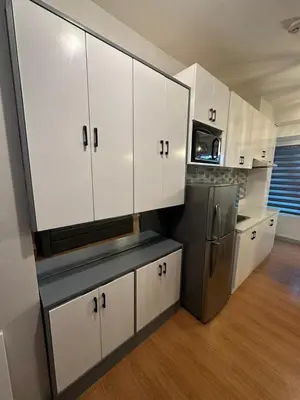 a kitchen with white cabinets and a stainless steel refrigerator at Newly Reneuvated Fully Furnished Condo Apartment in the Heart of Mandaluyong in Manila