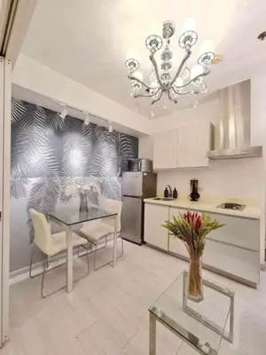 a kitchen with a glass table and a chandelier at Azure Urban Resort Residences Paranaque Near Airport and Mall in Manila