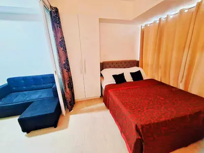 a bedroom with a red bed and a blue couch at Azure Urban Resort Residences Paranaque Near Airport and Mall in Manila