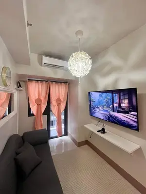 a living room with a couch and a flat screen tv at Sofia's place shore 3 tower 2 in Manila