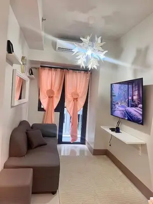 a living room with a couch and a tv and a window at Sofia's place shore 3 tower 2 in Manila