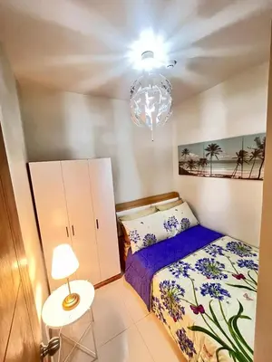 a small bedroom with a bed and a chandelier at Sofia's place shore 3 tower 2 in Manila