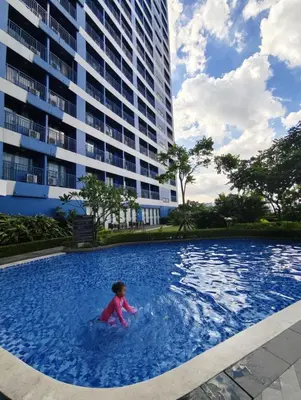 a child in a swimming pool in a building at Air Residences Suite by Christine Suites PH in Manila