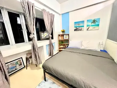a bedroom with a bed in a room with windows at BGC McKinley Apartment B1 in Manila