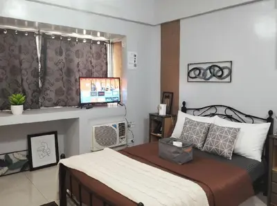 a bedroom with a bed and a flat screen tv at Cozy Home in BGC McKinley B2 in Manila