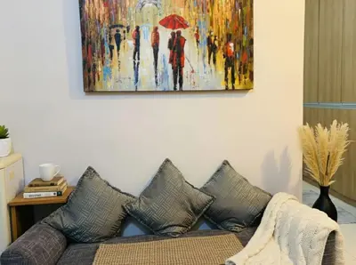a couch in a living room with a painting on the wall at Heart of BGC McKinley B3 in Manila
