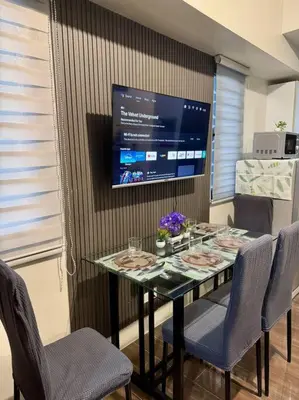 a dining room table with chairs and a tv at Air Residences 43rdF -By Soliel in Manila