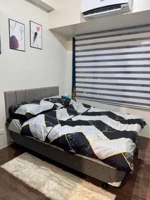 a bedroom with a bed with a comforter and a window at Air Residences 43rdF -By Soliel in Manila