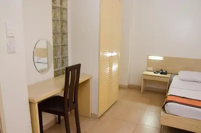 a bedroom with a desk and a bed and a mirror at M Suites Hotel in Manila