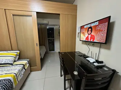 a bedroom with a desk and a tv on the wall at SD2 tandem staycation in Manila