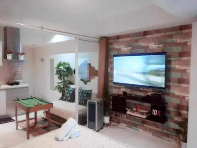 a living room with a brick wall with a flat screen tv at 225 St Tropez Tower Azure Urban Resort Residences in Manila