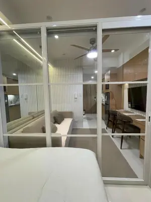 a bedroom with glass walls and a bed and a table at Antoneitte Staycation in Manila