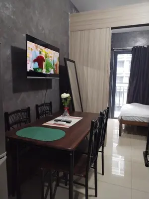 a dining room table with chairs and a television on the wall at Casa Reyes in Manila
