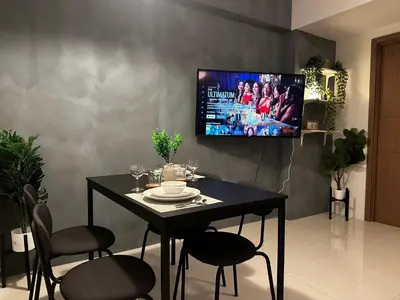 a dining room with a table and a tv on a wall at 1BR Stay near NAIA Terminal 3 via Runway Manila in Manila