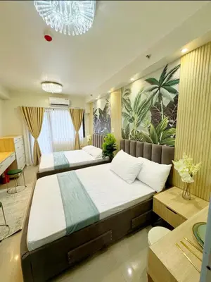 a bedroom with two beds and a mural of palm trees at Plete's Suite in Manila