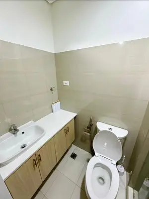 a bathroom with a white toilet and a sink at Plete's Suite in Manila