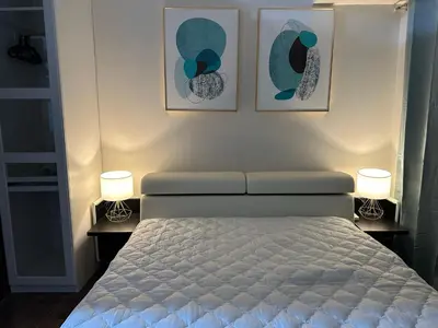 a bedroom with a bed with two lamps and two pictures at Queen size bed at Air Ayala Ave Makati in Manila