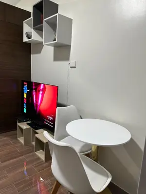 a white dining room with a table and a tv at Queen size bed at Air Ayala Ave Makati in Manila