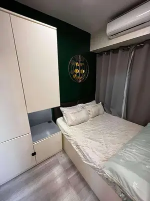 a small bedroom with a bed and a green wall at Stylish and Modern Suite with Pool Access and Parking in Manila