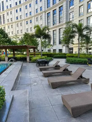 a patio with lounge chairs and a pool in front of a building at 81 Newport Blvd Cluster 4 Unit 10C by Rechelle Nunag in Manila